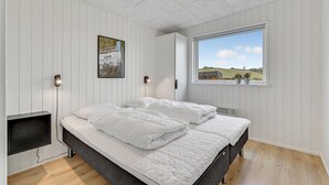 A bedroom with a bed, a bedside table, a wall-mounted lamp, a window with a view, and a framed picture on the wall. - Pet friendly home in Løgstrup with WiFi (Løgstrup)