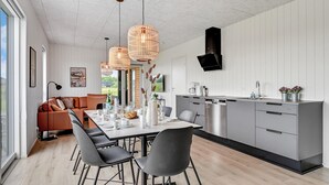 A modern kitchen with a dining area, featuring a long table, grey chairs, and a central island with a sink and appliances. - Pet friendly home in Løgstrup with WiFi (Løgstrup)