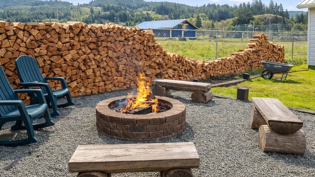 A fire pit with logs, outdoor seating, and a view of a forested hill. - North Sunrise Studio - Retreat in Forks (Forks)