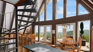 A spacious room with a wooden dining table, chairs, and a spiral staircase. Large windows offer views of the outdoors.