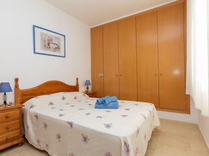 Une chambre à coucher avec un lit en bois, une table de chevet, une armoire et un tableau encadré au mur.