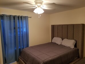A bedroom with a bed, curtains, and a ceiling fan. - Seasonal Renters (St Petersburg)