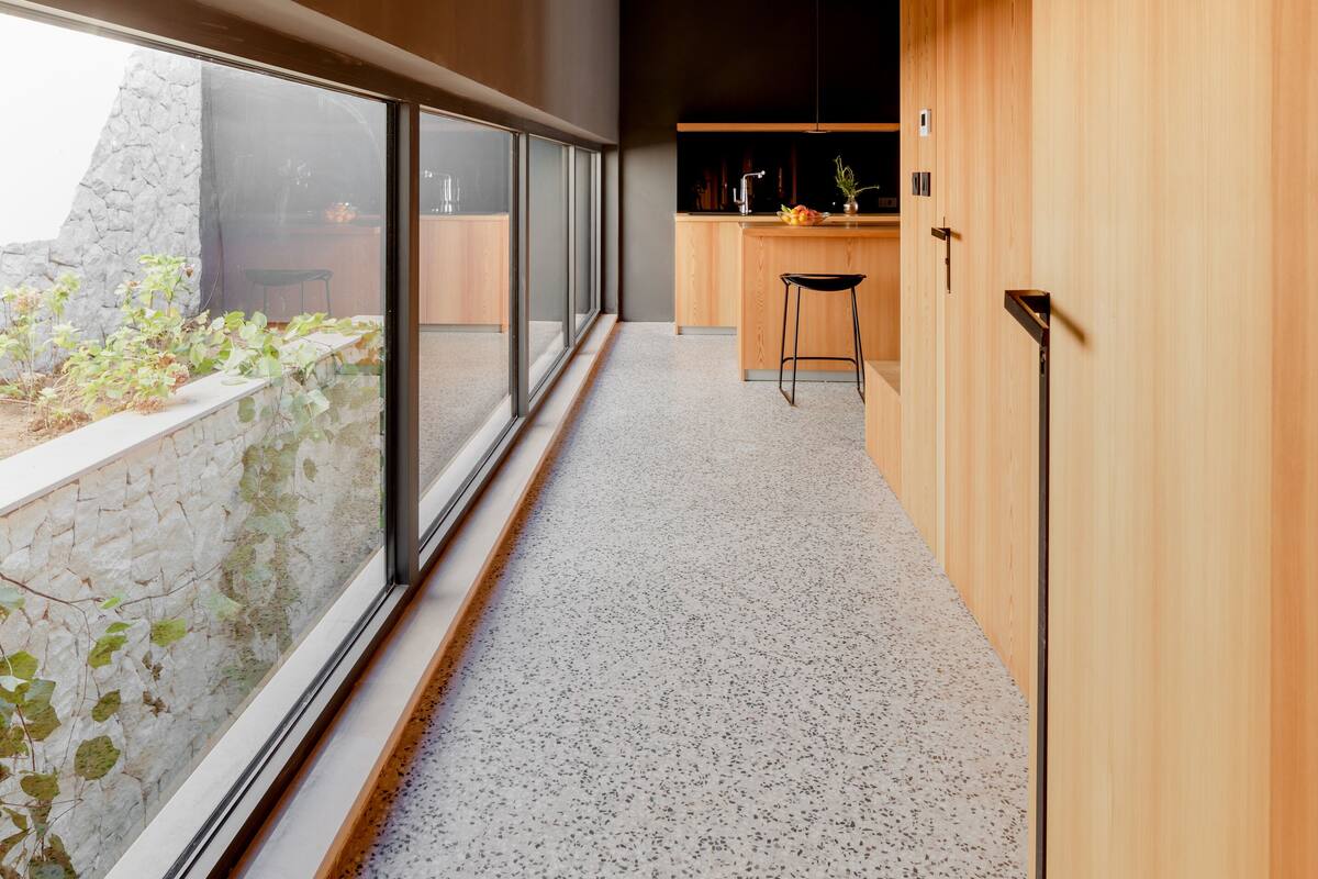 A modern kitchen with a large window, a kitchen island, and a stone wall outside.