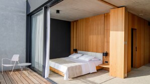Un dormitorio moderno con una cama grande, una mesita pequeña y una silla.