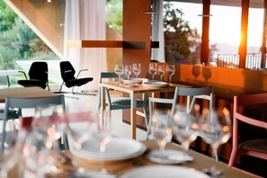 Un restaurant avec une table dressée pour un repas, des chaises et une vue sur l’extérieur.