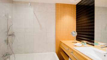 Une salle de bain moderne avec une baignoire, un meuble-lavabo en bois, un miroir et une douche.