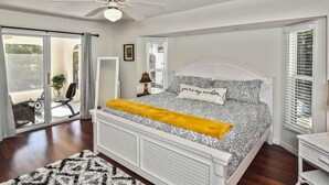 A bedroom with a bed, a ceiling fan, a window, and a sliding glass door leading to an outdoor area.