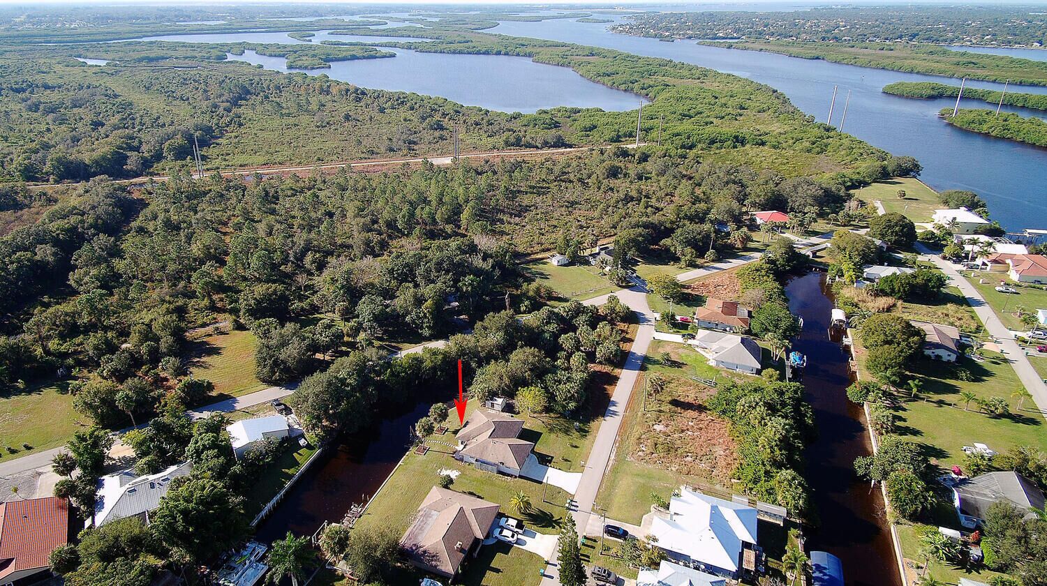 Vue aérienne d’un quartier résidentiel avec des maisons, une rivière et un pont.