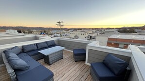 Une terrasse sur le toit aménagée avec un canapé d’angle, une petite table et un banc rembourré.