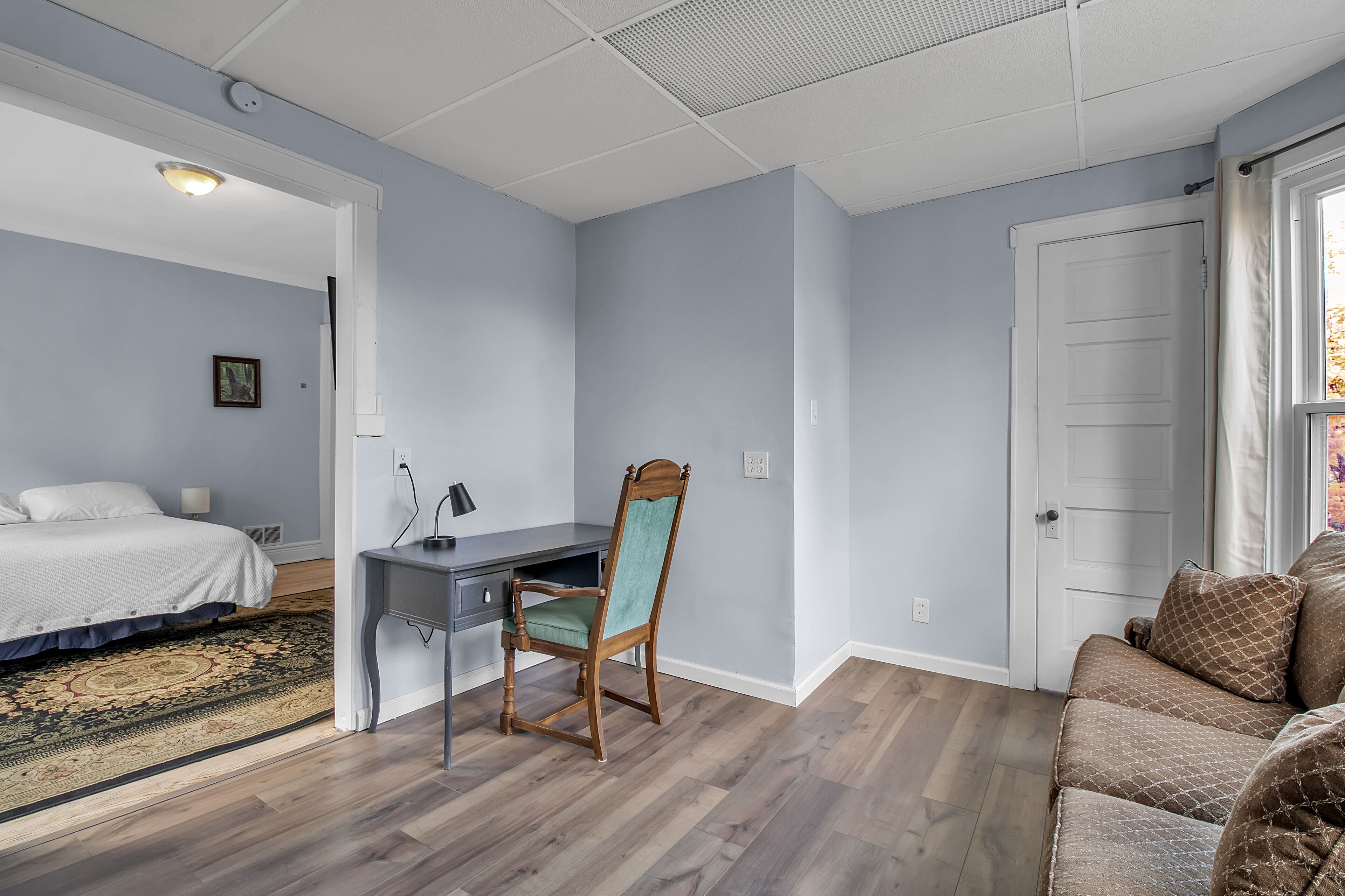 A bedroom with a bed, a desk, and a chair.