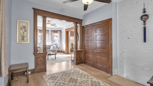 A hallway with wooden doors, a ceiling fan, a patterned rug, and a framed picture on the wall. - Spacious Historical Home by Parks, Shops, 4bd 2ba Save Weekly & monthly. (Buffalo)