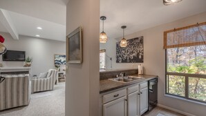 A modern kitchen with granite countertops, white cabinetry, and pendant lighting.