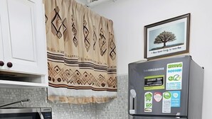 Une cuisine de taille réduite, avec des meubles blancs, un four à micro-ondes, une cuisinière et un réfrigérateur.
