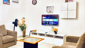Un salon moderne doté d’un téléviseur à écran plat, de canapés confortables, d’une table basse et d’un vase décoratif.