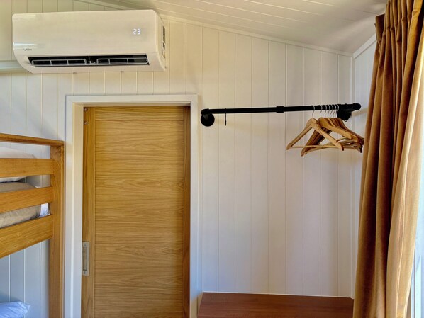 A room with a bunk bed, a wooden door, an air conditioning unit, a coat rack, and a curtain. - Lovedale Abode 13 bedrooms with heated pool & Acres (Lovedale)