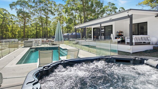 A modern outdoor pool area with a hot tub, lounge chairs, and a covered seating area. - Lovedale Abode 13 bedrooms with heated pool & Acres (Lovedale)