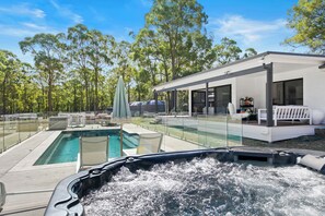 A modern outdoor pool area with a hot tub, lounge chairs, and a covered seating area. - Lovedale Abode 13 bedrooms with heated pool & Acres (Lovedale)