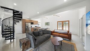 A spacious living area with a curved staircase, a gray sofa, a brown leather couch, and a dining table. - Lovedale Abode 13 bedrooms with heated pool & Acres (Lovedale)