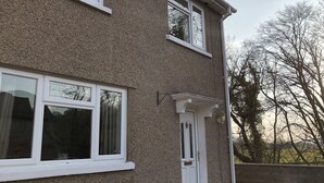 Ein zweistöckiges Haus mit weiß umrandeten Fenstern und einer weißen Tür.