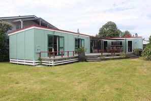 A light green building with a red roof, a covered porch, and a satellite dish.