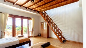 A bedroom with a wooden ceiling, a bed, a bench, a staircase, and a balcony with outdoor furniture. - D'Canggu Homestay (Canggu)