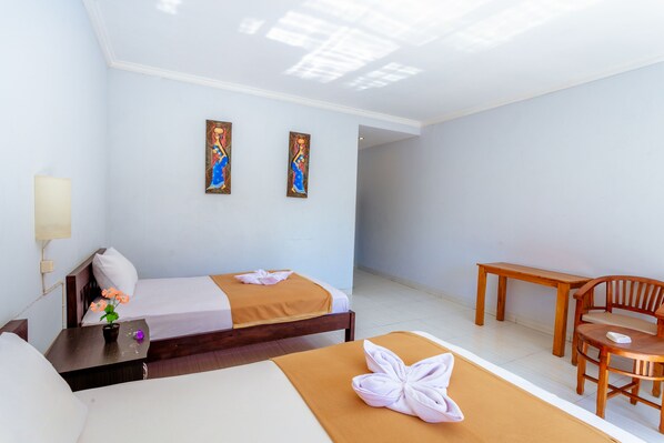 Une chambre d’hôtel avec deux lits, une table en bois, une chaise et deux tableaux au mur.