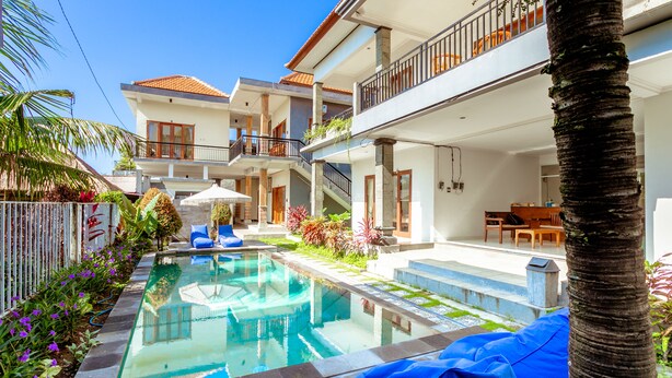 A modern hotel with a swimming pool, outdoor seating, and a balcony with a view. - D'Canggu Homestay (Canggu)