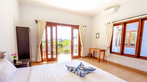 A hotel room with a bed, a desk, a wardrobe, and a balcony with a view. - D'Canggu Homestay (Canggu)
