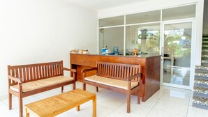 A room with a wooden bench, a wooden table, and a counter with a water dispenser. - D'Canggu Homestay (Canggu)