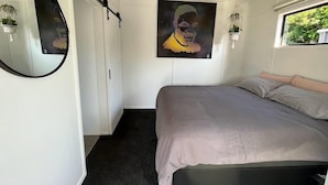Een slaapkamer met een bed, een ronde spiegel en een schilderij aan de muur.