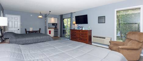 A bedroom with a large bed, a dresser, a TV, and a chair.