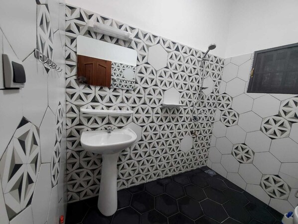 A bathroom with a geometric patterned wall, a white pedestal sink, and a shower area. - 2 bedrooms - Luxury apartment Mènontin (Cotonou)