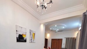Ein Essbereich mit einem Glastisch, schwarzen Stühlen und einer Chandelier. Zwei gerahmte Kunstwerke sind an der Wand zu sehen.