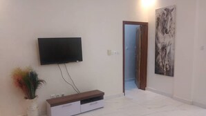 Ein modernes Wohnzimmer mit Flachbildfernseher an der Wand, einer Holz-Unterhaltungseinrichtung und einem großen abstrakten Gemälde.