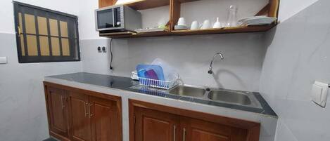 Una cocina pequeña con gabinetes de madera, un microondas y un lavamanos.