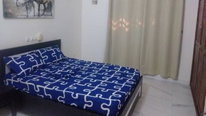 Ein Schlafzimmer mit Bett, Gemälde, Klimaanlage und Vorhang.
