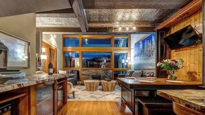 Una cucina moderna con camino in pietra, mobili in legno e un'ampia finestra che si affaccia su un paesaggio innevato.