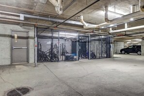 Eine Parkgarage mit Betonböden, Metallbarrieren und einigen parkenden Autos.
