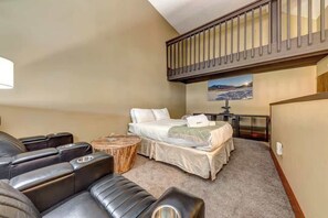 Ein Schlafzimmer mit einem Bett, einem Massagesessel, einem kleinen runden Tisch und einem Bild an der Wand.