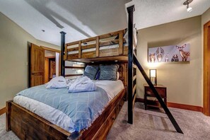 Ein Stockbett mit Holzrahmen, ein Nachttisch und eine Wandlampe.