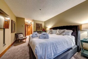Ein Hotelzimmer mit einem großen Bett, einem Sessel, einem Schreibtisch und einer Lampe.