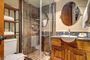 Ein Badezimmer mit einer gläsernen Duschkabine, einem Holzausziehtisch mit Waschbecken und einem Spiegel darüber.