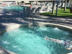A swimming pool with a diving board, lounge chairs, and a grassy area with a fence. - Lovely bright high ceilings condo (KISSIMMEE)