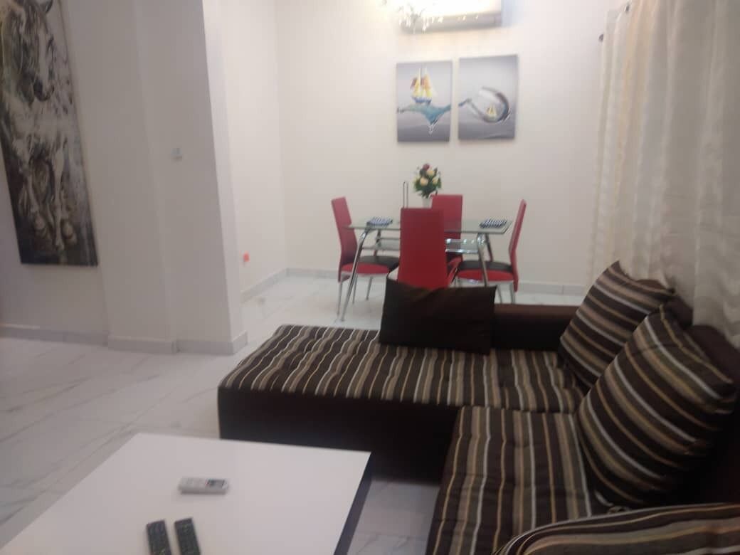 Uma sala de estar com um sofá listrado, uma mesa de jantar com cadeiras vermelhas e obras de arte nas paredes.