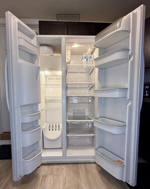 An open refrigerator with multiple shelves and a water dispenser.