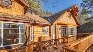 A log cabin with a deck, large windows, and a wooden bench. - Private tree top cabin, Mountain Views, 5 min to slopes, Walk to zoo & food (Big Bear)