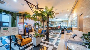 A hotel lobby with a check-in counter, seating area, and a large plant. - Griffin Bay Hotel (Busan)