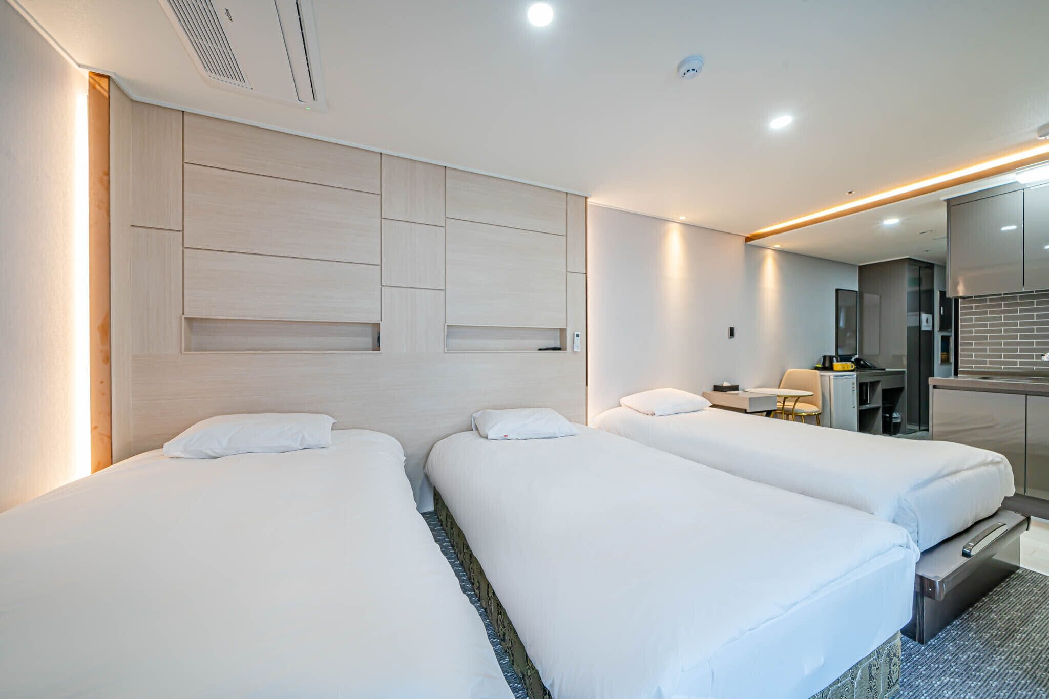 A hotel room with two beds, a desk, and a bathroom.