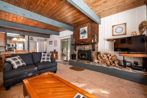 A cozy living room with a fireplace, a sofa, a coffee table, and a television. - Walk 240 yds to Resort+Steps to Hot Tub/Free Town/Ski Bus-Wood Stove/Cabin Like Setting-Covered Deck (Steamboat Springs)