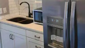 A kitchen with white cabinets, a stainless steel refrigerator, a black sink, and a microwave. - Stylish one bedroom apartment in downtown Jackson (Jackson)